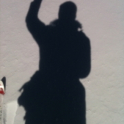 Shadow of person waving on pavement.