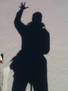 Shadow of person waving on pavement.