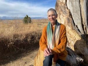 Person sitting by a large tree outdoors.